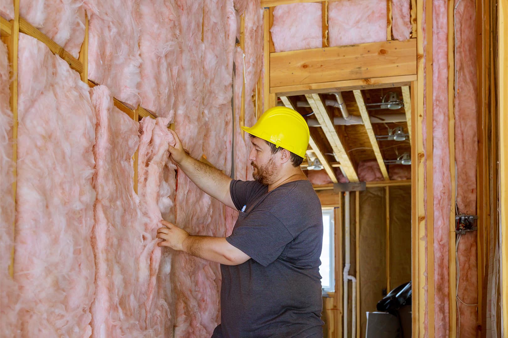 man installing thermal insulation layer wall using mineral wool
